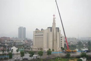 A cross is being removed from atop a large church.