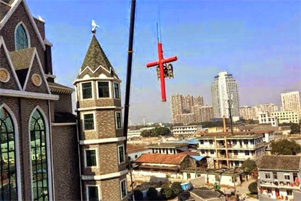 A cross is being removed from a building.