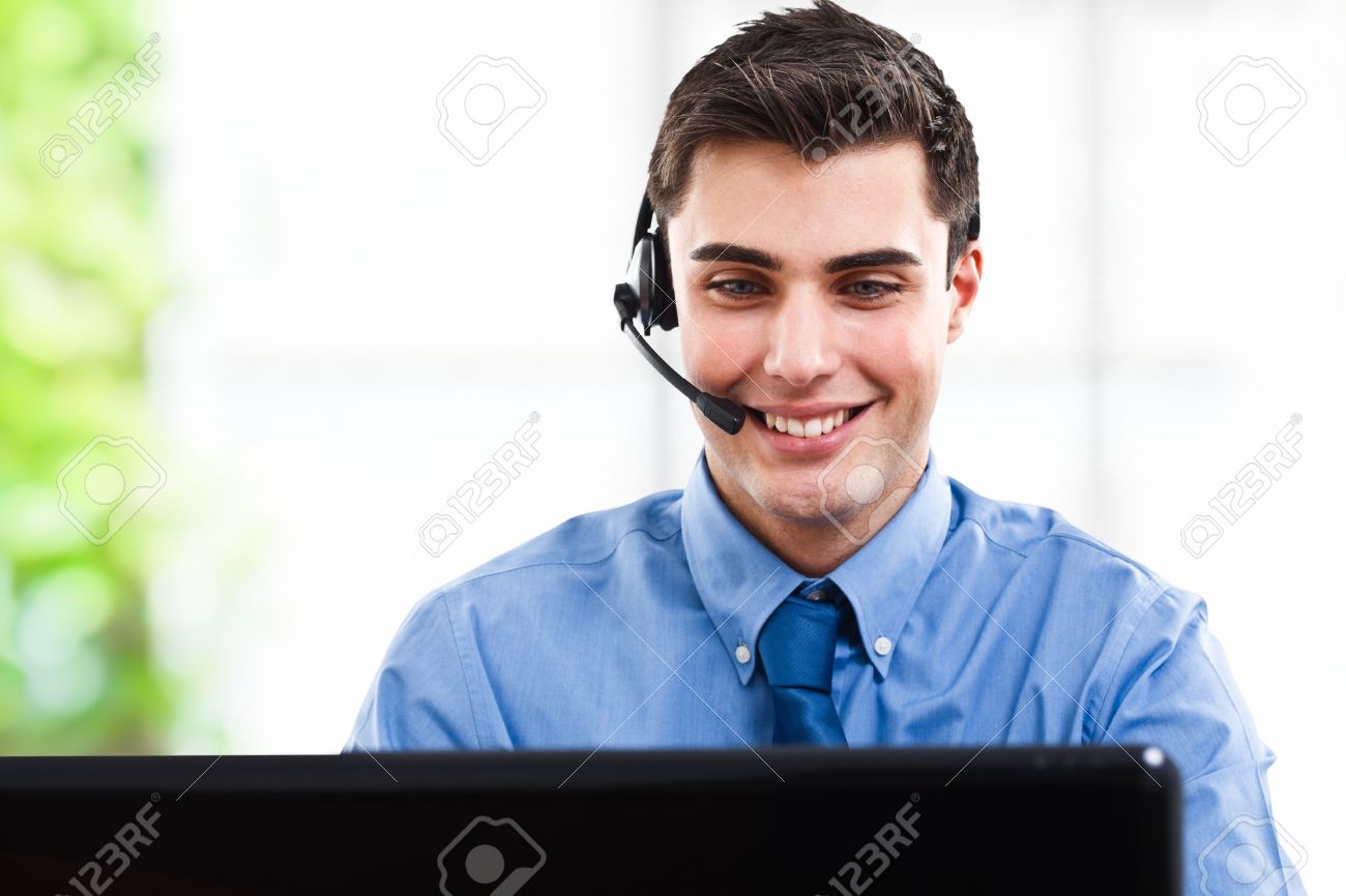 14748650-Handsome-man-using-an-headset-in-front-of-a-computer-screen-Stock-Photo.jpg