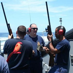 I am the bald one in the middle teaching others how to skeet shoot clay pigeons