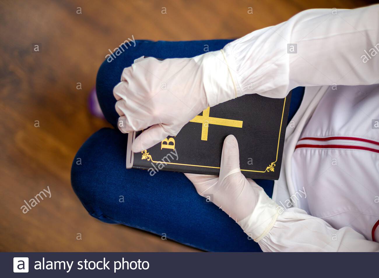 person-nurse-or-doctor-with-gloves-stand-in-prayer-with-bible-in-hand-the-infected-person-stands-in-prayer-with-the-bible-in-his-hand-2BC0R9F.jpg