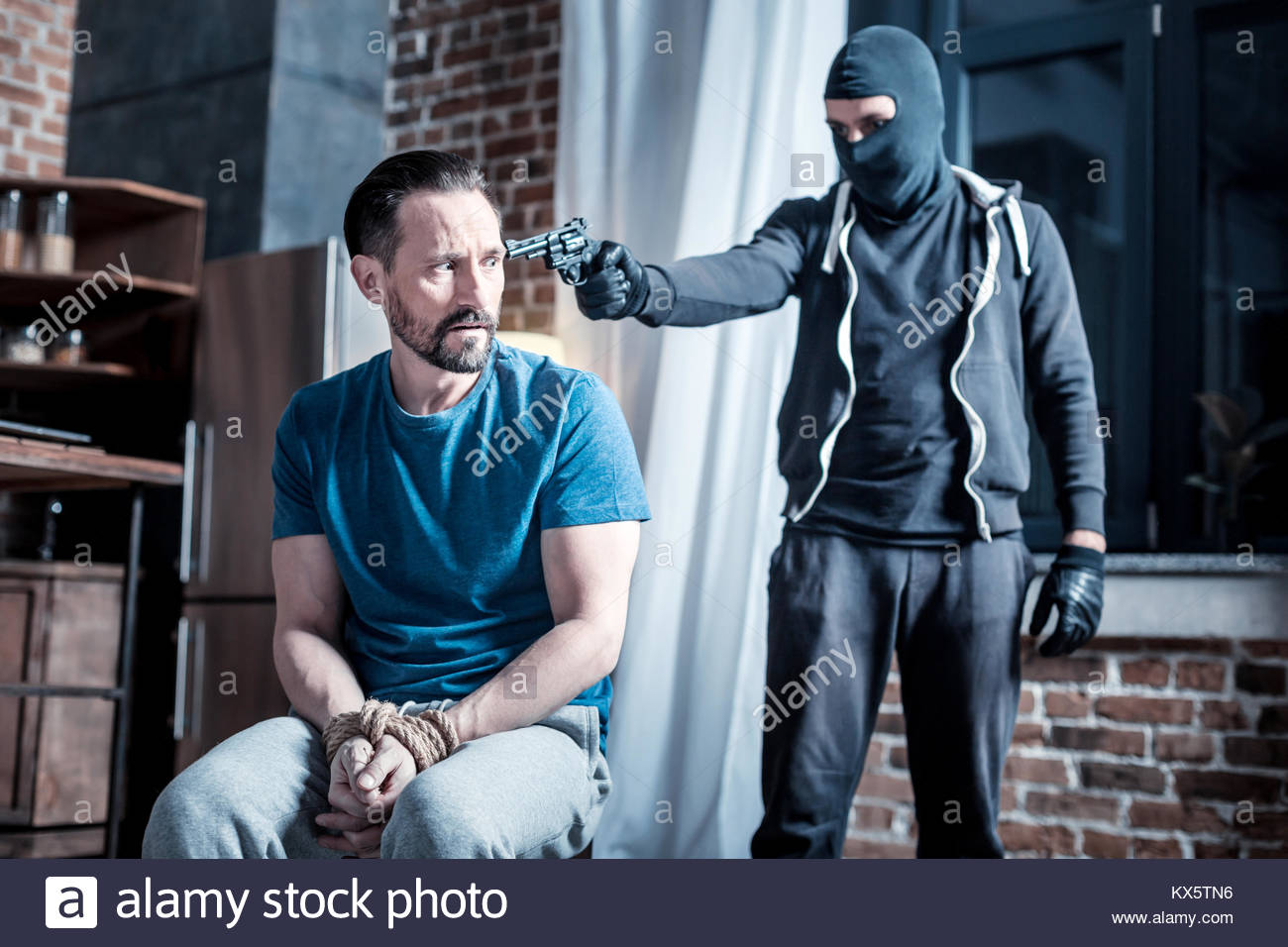 masked-criminal-holding-a-pistol-to-mans-head-KX5TN6.jpg