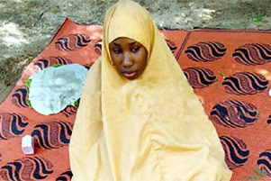 Leah is sitting on a blanket, wearing a hijab.