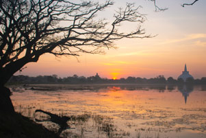 A scenic view of the Anuradhapura District with a lake in the foreground and a town in the background