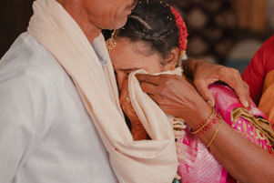 Woman in sari, crying on her father's shoulder