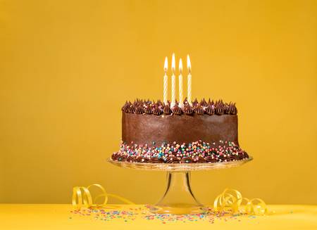 78950882-chocolate-birthday-cake-with-colorful-sprinkles-and-candles-over-yellow-background-.jpg