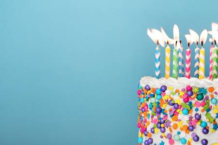 119041436-birthday-cake-with-lots-of-colorful-candles-and-sprinkles-on-a-blue-background.jpg