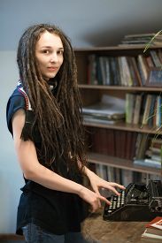 girl-dreadlocks-scarf-standing-library-typing-typewriter_cg2p63155891c_th.jpg